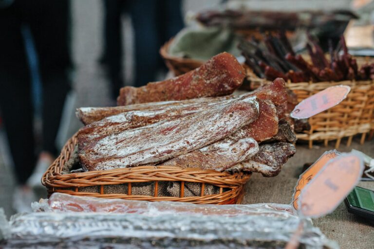 A basket of seasoned and dried beef and pork at a rustic food market.